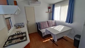 a small kitchen with a stove and a table in a room at MOBILE HOME Klenovica SONČEK in Klenovica