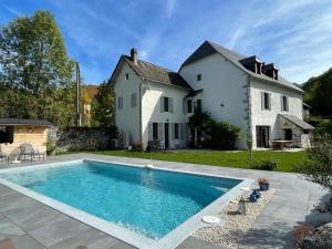 Accous的住宿－L 'Air d'Aspe，房子前面的房子和游泳池