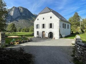 un bâtiment blanc avec une montagne en arrière-plan dans l'établissement L 'Air d'Aspe, à Accous