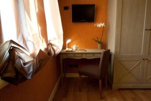 Habitación con escritorio, TV y silla. en Hotel Locanda Stendhal, en Colorno