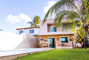una casa con una palma di fronte di Excelente casa com Piscina a Camaçari