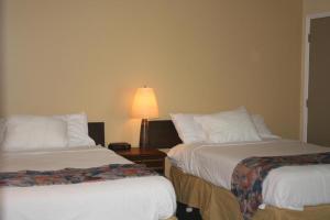 a hotel room with two beds and a lamp at Carolyn Beach Inn in Thessalon