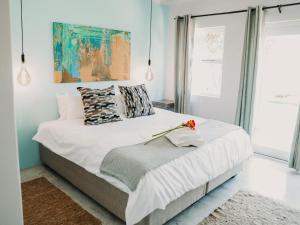 a bedroom with a white bed with a painting on the wall at Giardino Boutique Hotel in Swakopmund