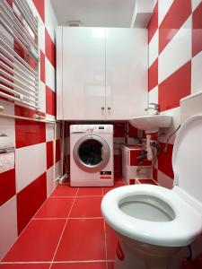 a red and white bathroom with a toilet and a washing machine at National Arena Mega Mall Elana apartment in Bucharest