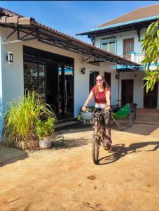 a woman riding a bike in front of a house at Siem Reap home in Siem Reap
