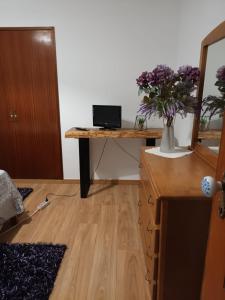 a desk with a vase of purple flowers on it at vivenda do Sobreiro AL in Serpins