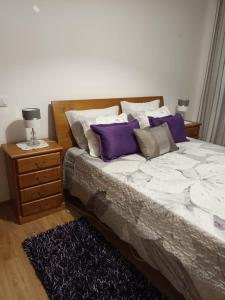 a bedroom with a bed with purple pillows and a nightstand at vivenda do Sobreiro AL in Serpins