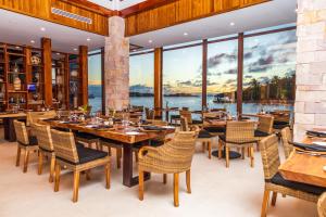 un restaurante con mesas, sillas y ventanas grandes en Anthony's Key Resort en Sandy Bay