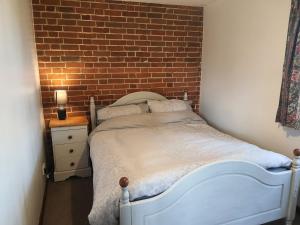 a bedroom with a white bed and a brick wall at Cosy Rural Barn Conversion 5 Min Drive To Pin Mill 1 BR + sofa bed 