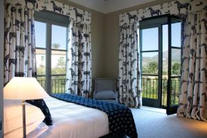 1 dormitorio con 1 cama y balcón con ventanas en Finca Cortesin Hotel Golf & Spa en Casares