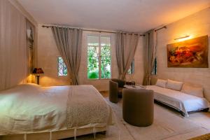 a bedroom with a bed and a couch and a window at Prestige du Souss in Oulad Berhil