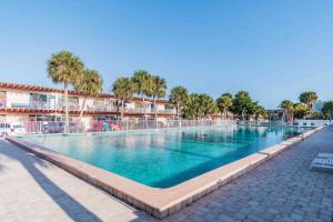 a large swimming pool in a resort with palm trees at Seaside Serendipity in Clearwater Beach