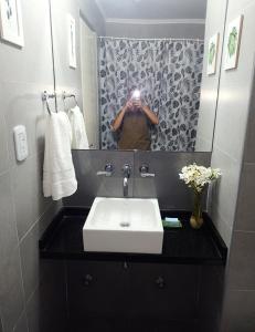 un hombre tomando una foto de un lavabo de baño en Monoambiente con vista al Rio Paraná en Ramallo