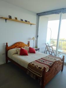 Un dormitorio con una gran cama de madera con almohadas rojas en Monoambiente con vista al Rio Paraná en Ramallo
