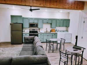 a living room with a couch and a kitchen with green cabinets at Sevier River Farmhouse 2 in Hatch