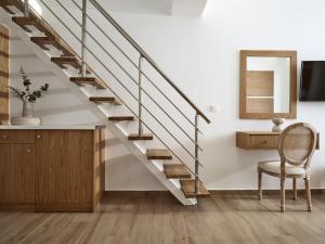 eine Treppe in einem Wohnzimmer mit einem Stuhl und einem Spiegel in der Unterkunft Stefania Apartments in Kypseli