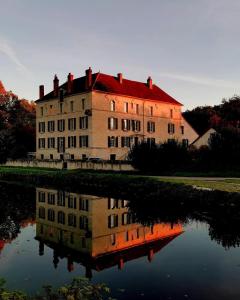 a large building with its reflection in the water at Le Moulin Neuf in Ancy-le-Franc