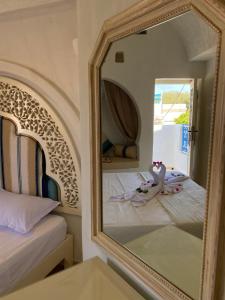 a mirror in a bedroom with two beds at Hôtel Djerba Authentique - Au centre de Midoun in Midoun