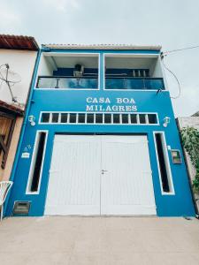 um edifício azul com uma porta de garagem branca em Pousada Casa Boa Milagres em Barra do Camaragibe