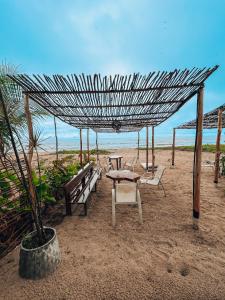 uma mesa de piquenique e cadeiras na praia em Pousada Casa Boa Milagres em Barra do Camaragibe