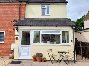 a small yellow house with a white door and a table at The Beehive - Self catering in the heart of the Forest of Dean in Whitecroft