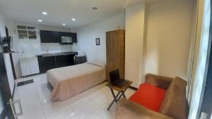 Un pequeño dormitorio con una cama y una cocina. en Apartaestudio Laureles la 33, en Medellín