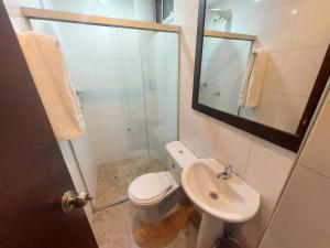 Un baño con inodoro, lavabo y espejo. en Apartaestudio Laureles la 33, en Medellín