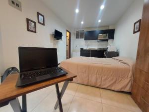 1 dormitorio con cama y escritorio con ordenador portátil en Apartaestudio Laureles la 33, en Medellín
