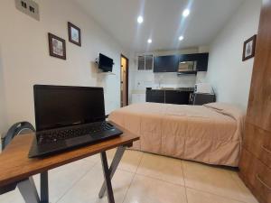 Un dormitorio con una cama y una computadora portátil en un escritorio. en Apartaestudio Laureles la 33, en Medellín