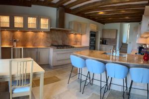 una cocina con una gran isla con taburetes de barra azul en La Bastide De Chassagne-Montrachet, en Chassagne-Montrachet