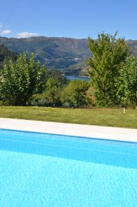 a blue swimming pool with a view of a mountain at Cantinho da Pedra in Vieira do Minho