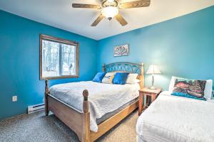 una camera da letto con pareti blu, un letto e un ventilatore a soffitto di Higgins Lake Retreat - Hike, Swim, Relax! a Roscommon