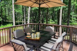 a table and chairs on a deck with an umbrella at Higgins Lake Retreat - Hike, Swim, Relax! in Roscommon