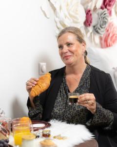 una mujer sentada en una mesa sosteniendo una hogaza de pan en Suite Romantique en Hésingue