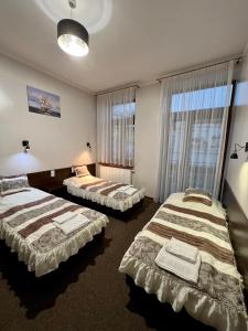 a hotel room with two beds and two windows at Apartamenty Ostrowiec - Pokoje Gościnne Centrum in Ostrowiec Świętokrzyski