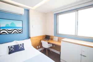 1 dormitorio con cama, escritorio y ventana en Barra da Tijuca de frente para o mar - 2 suítes até 6 pessoas em camas, en Río de Janeiro