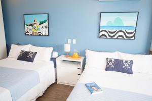 1 dormitorio con 2 camas y pared azul en Barra da Tijuca de frente para o mar - 2 suítes até 6 pessoas em camas, en Río de Janeiro