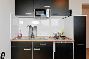 Stay&Dream - 75m² - Two Bedrooms - Kitchen - Netflix في إيسن: مطبخ بدولاب سوداء ومغسلة وثلاجة
