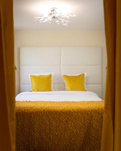 a bedroom with a bed with two yellow pillows at Suite-Airport-Basel in Blotzheim