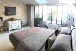 a bedroom with a bed and a desk and windows at Maison de Campagne in Beautiful Burgundy in Noyers-sur-Serein