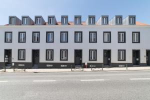 a large white building with black doors and windows at Ourique Charm Apartments in Lisbon