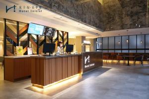 a man sitting at a reception desk in a hotel lobby at Hotel Initial-Taichung in Taichung