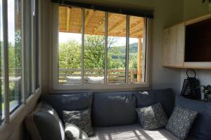 - un salon avec un canapé et 2 fenêtres dans l'établissement A LA BELLE ECORCE- tiny house, à Turenne