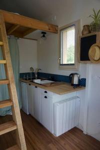 une cuisine avec des placards blancs et un comptoir dans l'établissement A LA BELLE ECORCE- tiny house, à Turenne