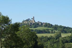 un château au sommet d'une colline plantée d'arbres dans l'établissement A LA BELLE ECORCE- tiny house, à Turenne