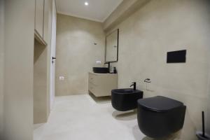 Un baño con un inodoro negro y un lavabo. en La Grand - New Bazaar, en Tirana