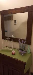 a bathroom counter with a mirror and flowers on it at Residenza nel borgo romano in Mentana