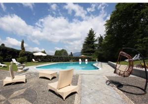 una piscina con 2 sillas y un columpio en Villa Ghiringhelli en Azzate