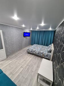 1 dormitorio con 1 cama y TV en la pared en Однокомнатная квартира в центре Петропавловска, en Petropavlovsk