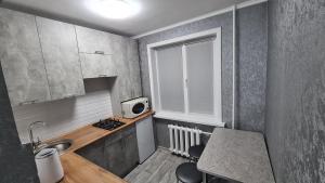una pequeña cocina con fregadero y microondas en Однокомнатная квартира в центре Петропавловска, en Petropavlovsk
